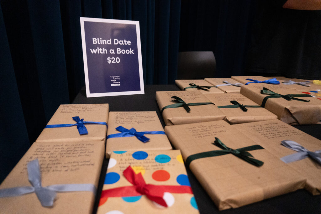 Books wrapped in brown paper and ribbon sit on a table with a sign reading " Blind Date with a Book $20"