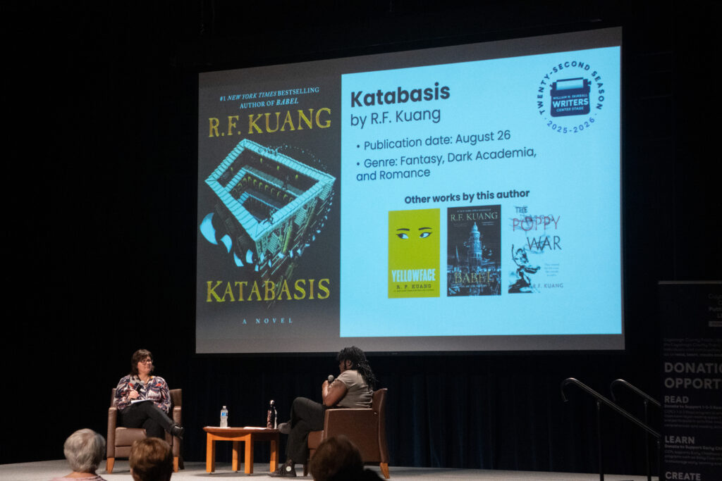 Angel Doughty and Kate Merlene talk about upcoming books while a slide behind them shows the cover of Katabasis by R.F. Kuang.